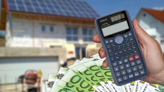Calculatrice et billets en euros devant une maison - déclaration revenus fonciers 2026