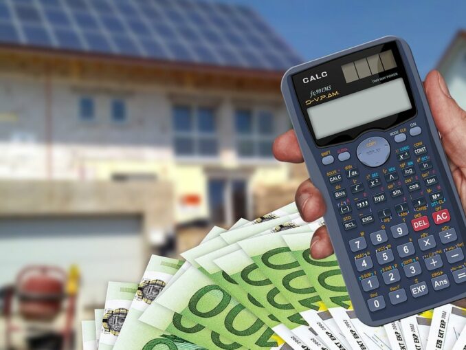 Calculatrice et billets en euros devant une maison - déclaration revenus fonciers 2026