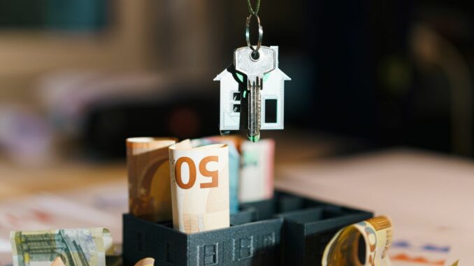 Clé de maison sur des billets euros, symbolisant la taxe foncière et les charges du propriétaire immobilier