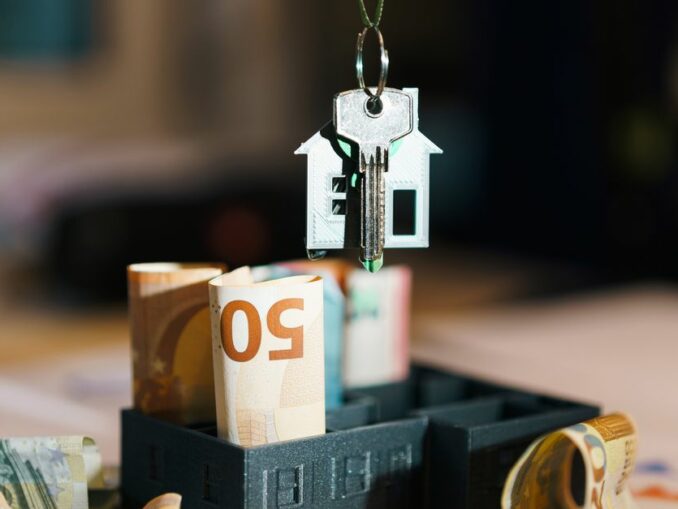 Clé de maison sur des billets euros, symbolisant la taxe foncière et les charges du propriétaire immobilier